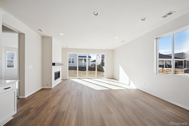 unfurnished living room featuring a healthy amount of sunlight and light hardwood / wood-style floors