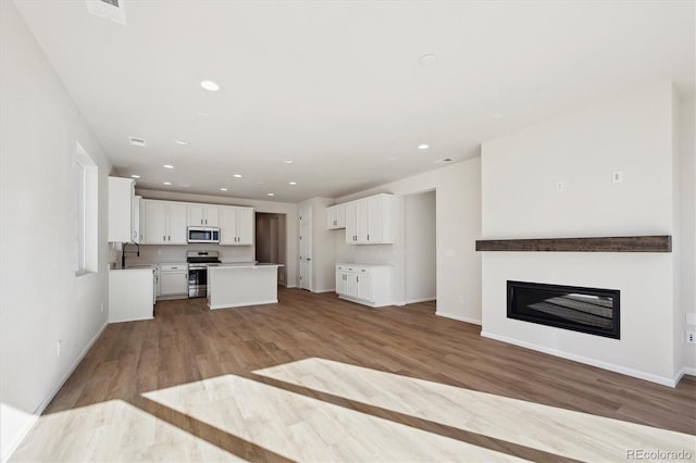 unfurnished living room featuring sink and light hardwood / wood-style flooring