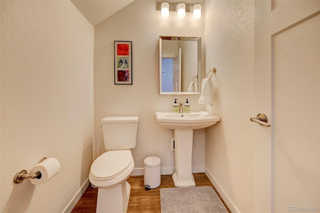 bathroom with hardwood / wood-style floors, toilet, sink, and vaulted ceiling