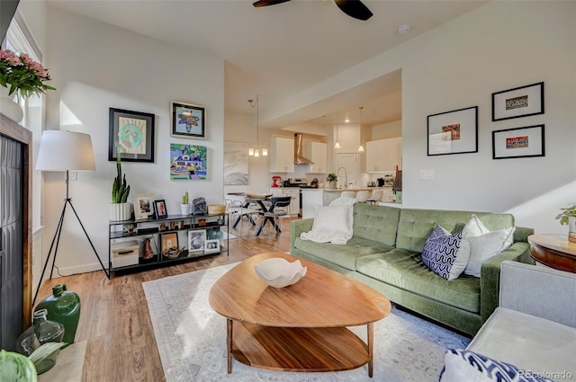 living room featuring ceiling fan, light hardwood / wood-style flooring, and sink