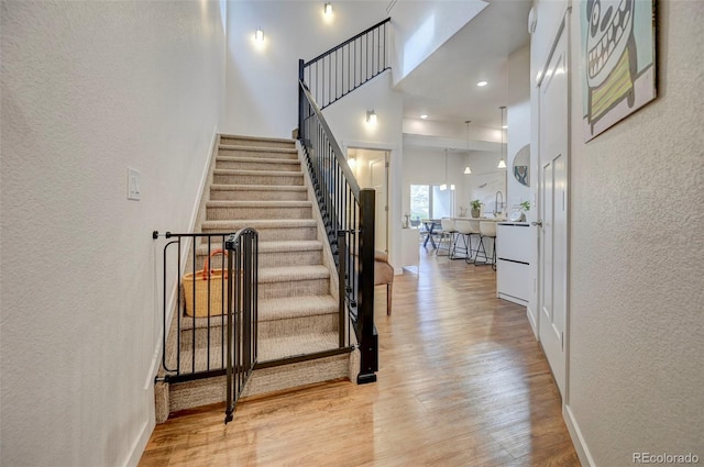 staircase with hardwood / wood-style floors and a towering ceiling