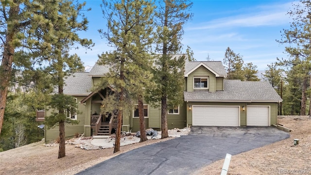 32555 Meadow Ridge Ln, Pine, CO 80470 - view of property hidden behind natural elements featuring driveway, a shingled roof, and an attached garage