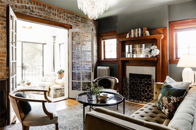 sitting room with radiator heating unit, a large fireplace, a healthy amount of sunlight, and light wood-type flooring