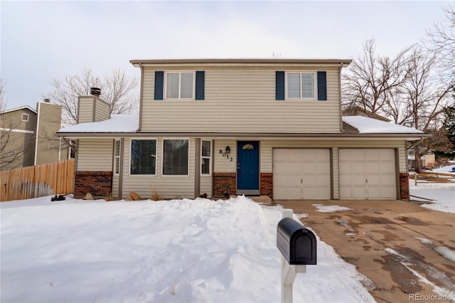 view of front of house with a garage, fence, brick siding, and driveway