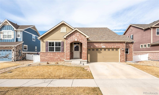 view of front facade featuring fence, driveway, an attached garage, a shingled roof, and brick siding