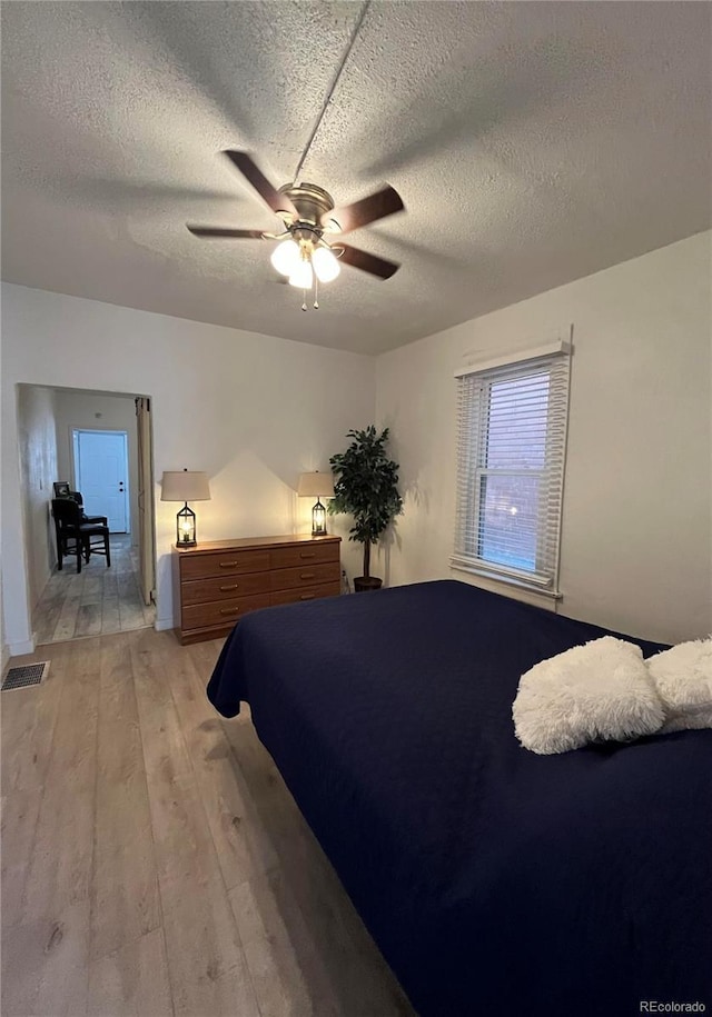 bedroom featuring ceiling fan, a textured ceiling, and light hardwood / wood-style flooring