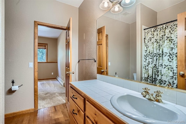 1361 Bross Ct, Evergreen, CO 80439 - bathroom featuring a textured wall, hardwood / wood-style flooring, baseboard heating, vanity, and a shower with shower curtain