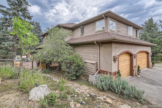 1361 Bross Ct, Evergreen, CO 80439 - view of side of property featuring an attached garage, asphalt driveway, roof with shingles, and stucco siding