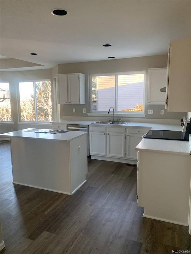 kitchen with a wealth of natural light, white cabinetry, sink, stove, and a kitchen island