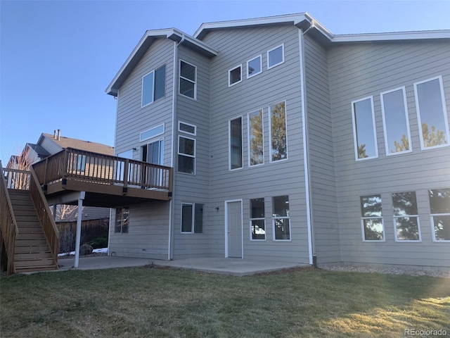 rear view of property featuring a lawn, a patio area, and a wooden deck