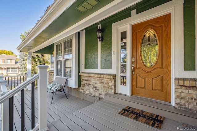 property entrance with covered porch and brick siding