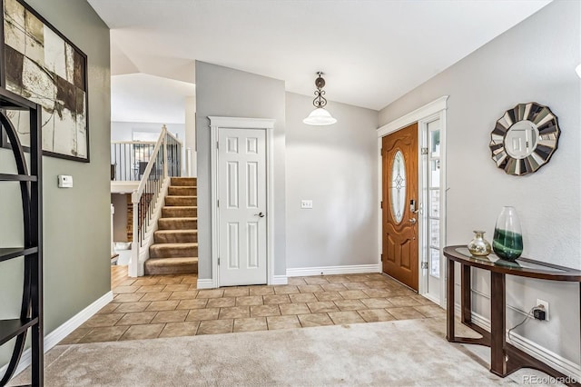 entrance foyer featuring carpet, tile patterned floors, baseboards, and stairs