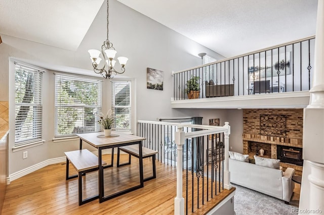 dining room with a brick fireplace, wood-type flooring, baseboards, and an inviting chandelier