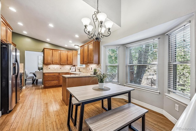 kitchen with vaulted ceiling, light wood-style floors, backsplash, and stainless steel fridge with ice dispenser