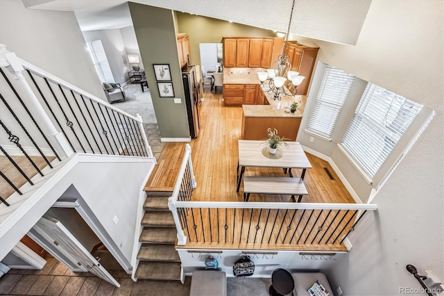 stairs featuring vaulted ceiling, baseboards, wood finished floors, and a notable chandelier