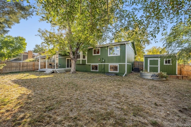 back of property featuring a fenced backyard, an outdoor structure, a storage unit, and central AC unit