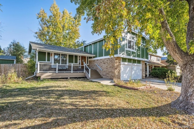 view of front of home with a porch, brick siding, fence, concrete driveway, and a front yard