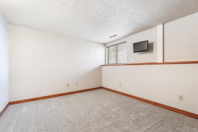 unfurnished room featuring baseboards, a textured ceiling, visible vents, and carpet flooring