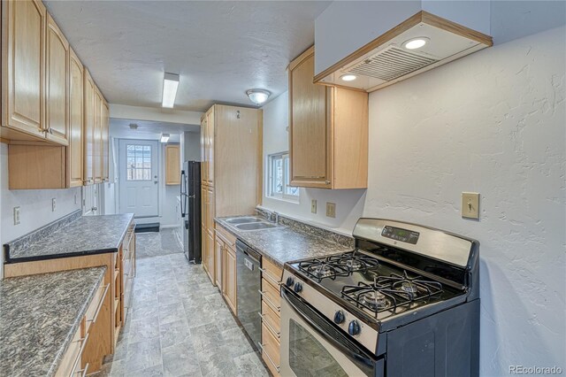 kitchen featuring dark countertops, freestanding refrigerator, stainless steel range with gas cooktop, dishwashing machine, and extractor fan