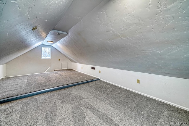 bonus room featuring baseboards, lofted ceiling, carpet flooring, a textured wall, and a textured ceiling