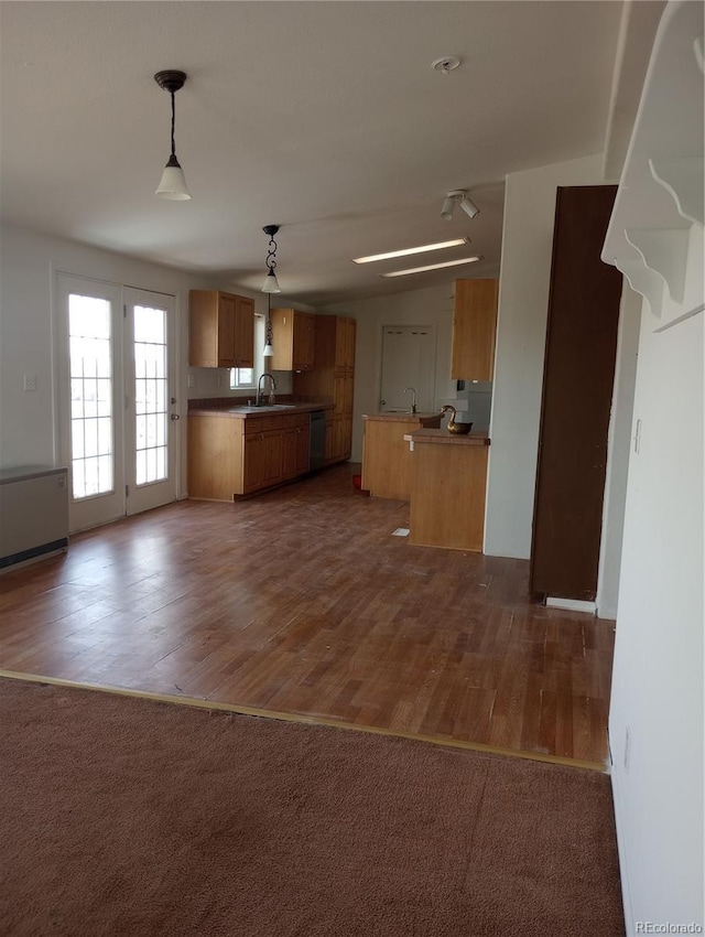 5511 Ridgetop Ct, Alamosa, CO 81101 - kitchen with brown cabinetry, dishwashing machine, open floor plan, hanging light fixtures, and dark wood-type flooring