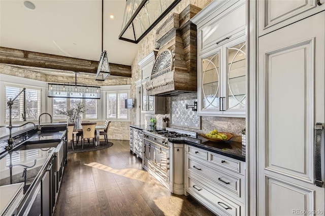 kitchen with custom exhaust hood, dark wood-type flooring, lofted ceiling with beams, tasteful backsplash, and decorative light fixtures