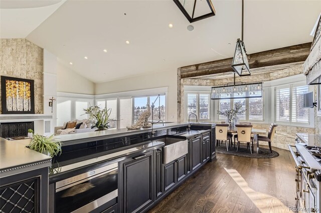 kitchen with sink, wall oven, dark hardwood / wood-style floors, lofted ceiling, and a fireplace