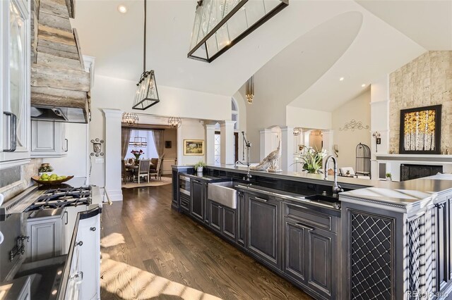 kitchen with ornate columns, sink, dark wood-type flooring, and vaulted ceiling