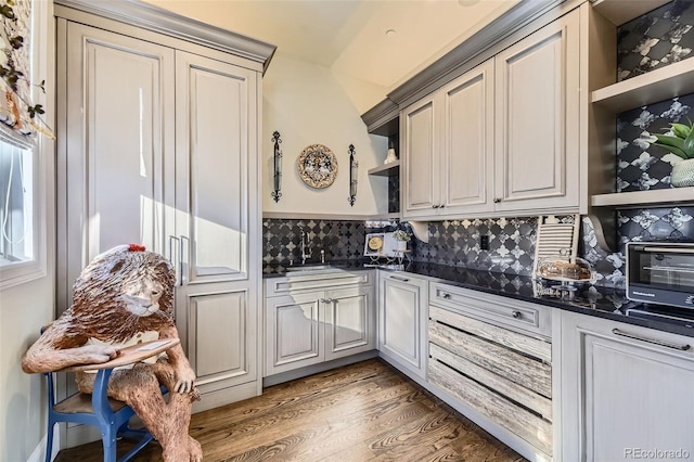 kitchen with decorative backsplash, dark hardwood / wood-style flooring, dark stone counters, and sink