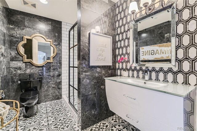 bathroom featuring tile patterned flooring, vanity, toilet, and tile walls