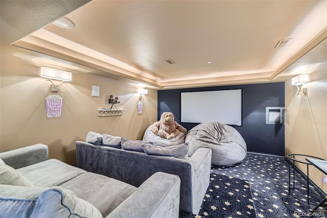 carpeted home theater room with a raised ceiling and an AC wall unit