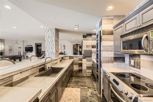 kitchen with light stone counters, sink, billiards, and stainless steel appliances