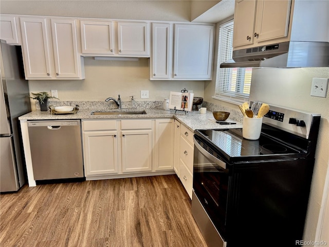 kitchen with sink, light hardwood / wood-style flooring, white cabinetry, stainless steel appliances, and light stone counters