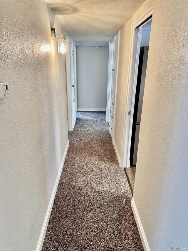 corridor featuring carpet flooring and a textured ceiling