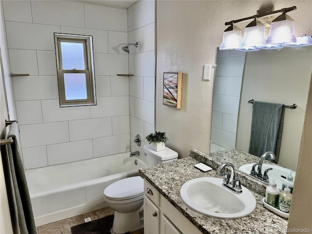 full bathroom featuring vanity, tiled shower / bath, and toilet