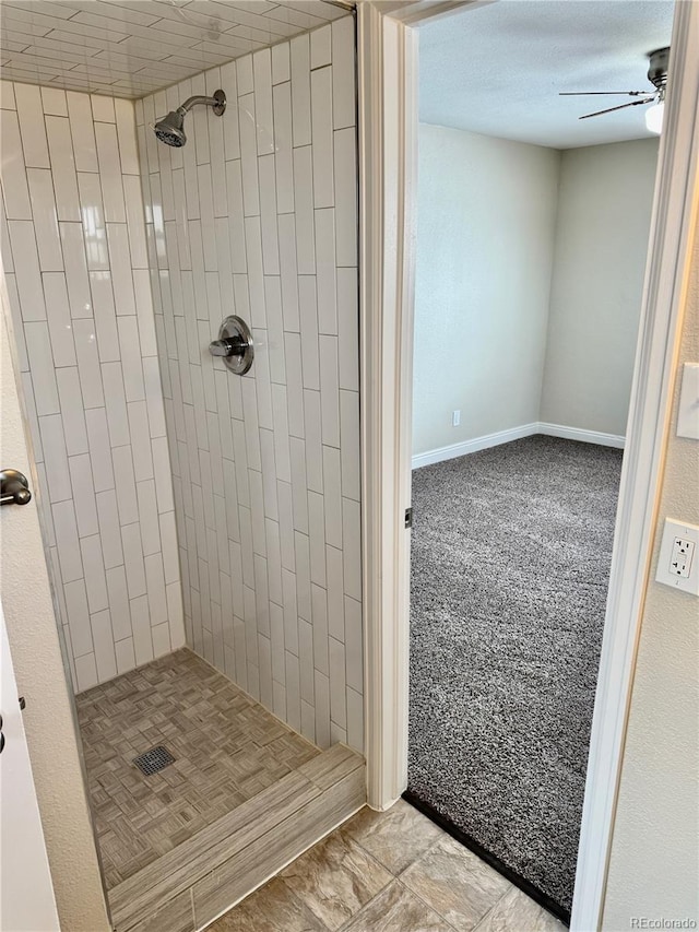 bathroom with a tile shower and ceiling fan