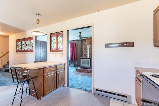 13705 County Road 45, Coaldale, CO 81222 - kitchen featuring a wood stove, a breakfast bar area, baseboard heating, light countertops, and a ceiling fan