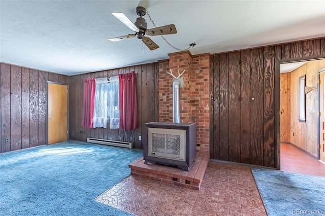 13705 County Road 45, Coaldale, CO 81222 - unfurnished living room with a wood stove, baseboard heating, a ceiling fan, wooden walls, and carpet floors