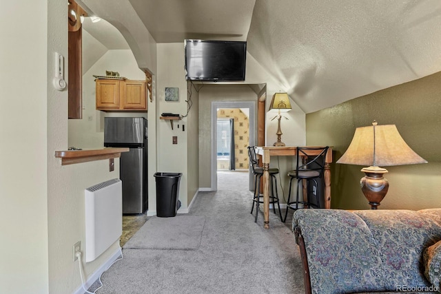 interior space with a textured ceiling, light carpet, and vaulted ceiling