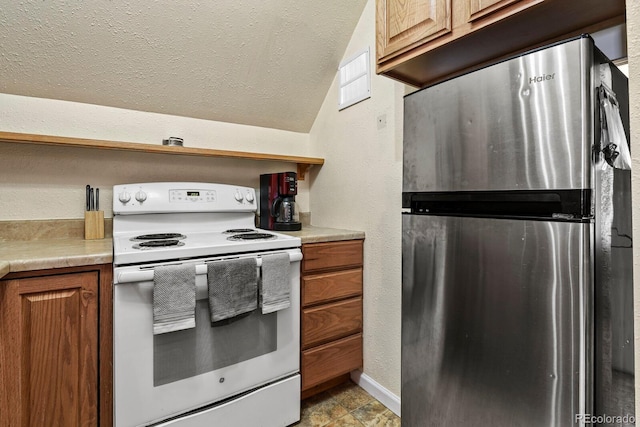 kitchen featuring vaulted ceiling, stainless steel fridge, light tile floors, and electric range