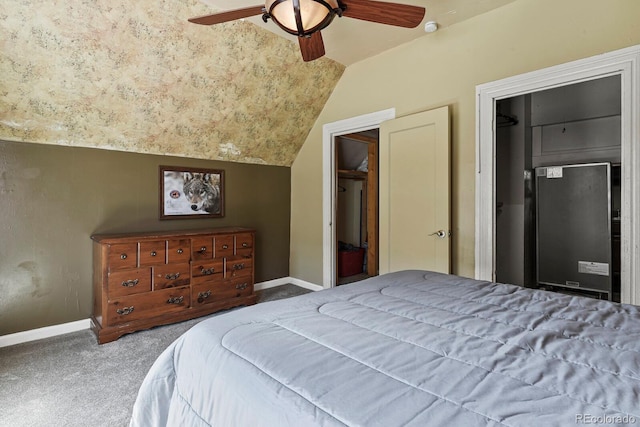 carpeted bedroom with ceiling fan, a walk in closet, a closet, and vaulted ceiling