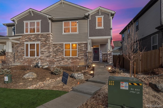 view of front facade with stone siding and fence