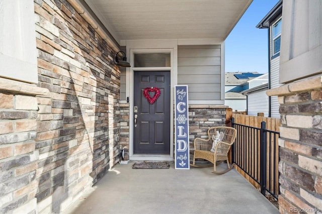 doorway to property with stone siding and fence