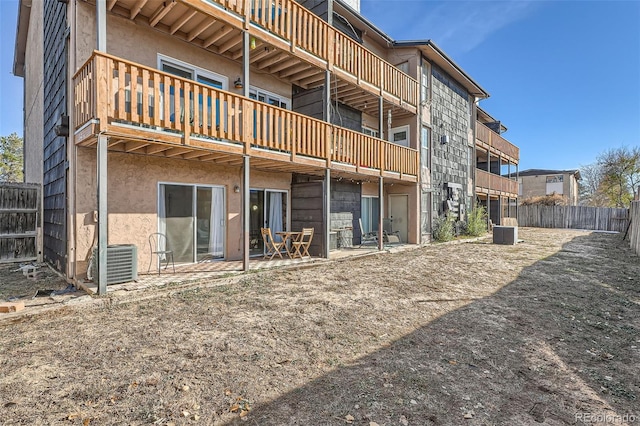 rear view of house featuring cooling unit, a patio area, fence, and stucco siding