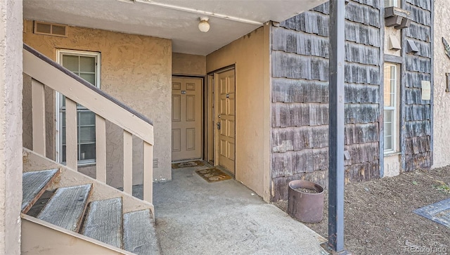 property entrance with visible vents and stucco siding