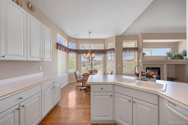 kitchen featuring a sink, light wood-style flooring, a chandelier, and white cabinets