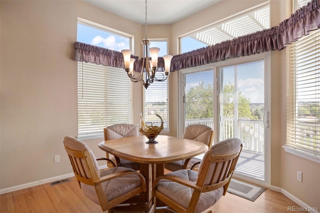 dining area featuring a chandelier, baseboards, light wood-style flooring, and healthy amount of natural light