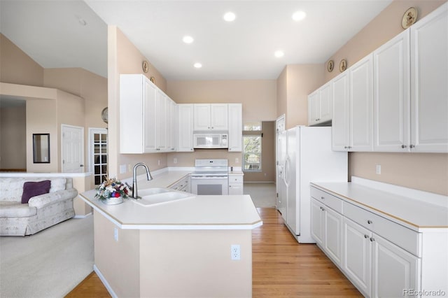 kitchen with white appliances, a sink, a peninsula, light countertops, and recessed lighting