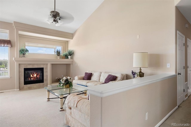 carpeted living room featuring a tiled fireplace, lofted ceiling, and baseboards