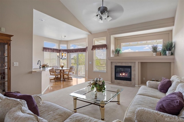 living area with a tile fireplace, ceiling fan, and high vaulted ceiling